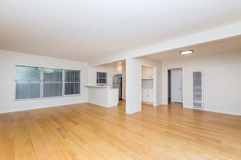 A spacious room with wooden floors and white walls.