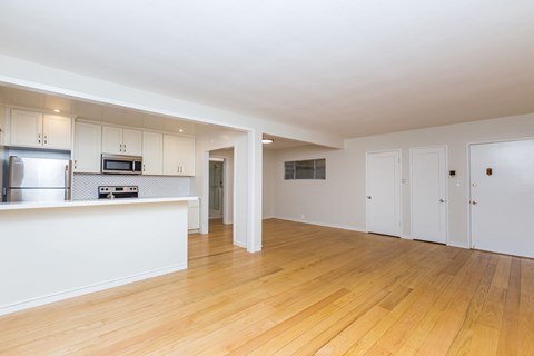 A kitchen with white cabinets and a wooden floor.