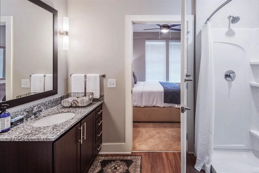 a bathroom with a sink and a shower and a bedroom