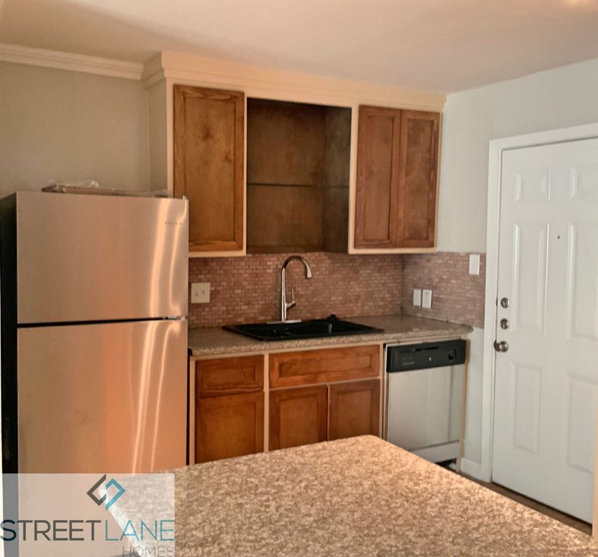 a kitchen with a sink and refrigerator and wooden cabinets