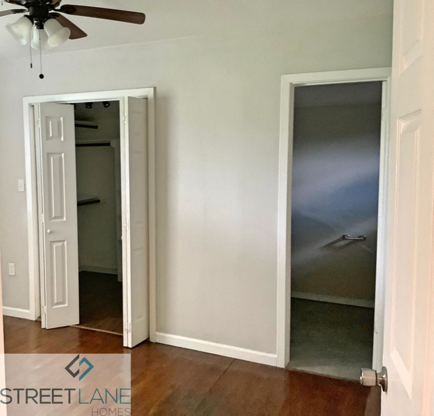 an open closet in a room with wood floors and a ceiling fan