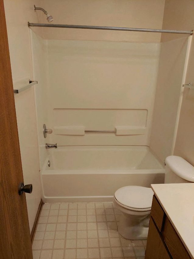 a white bathroom with a toilet and a bath tub