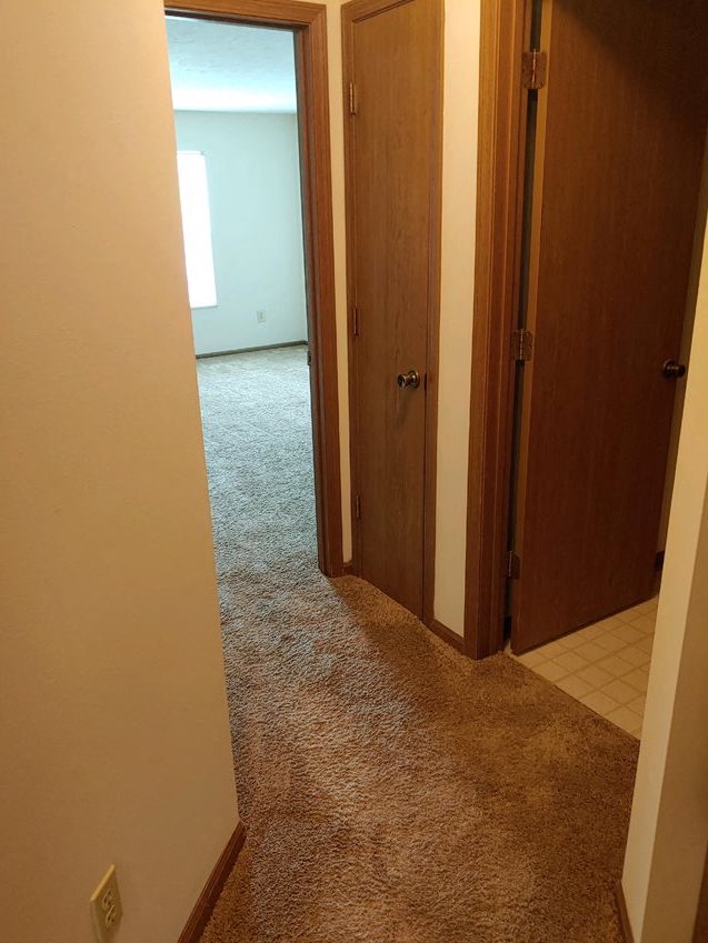 an empty hallway with two doors and a carpeted floor