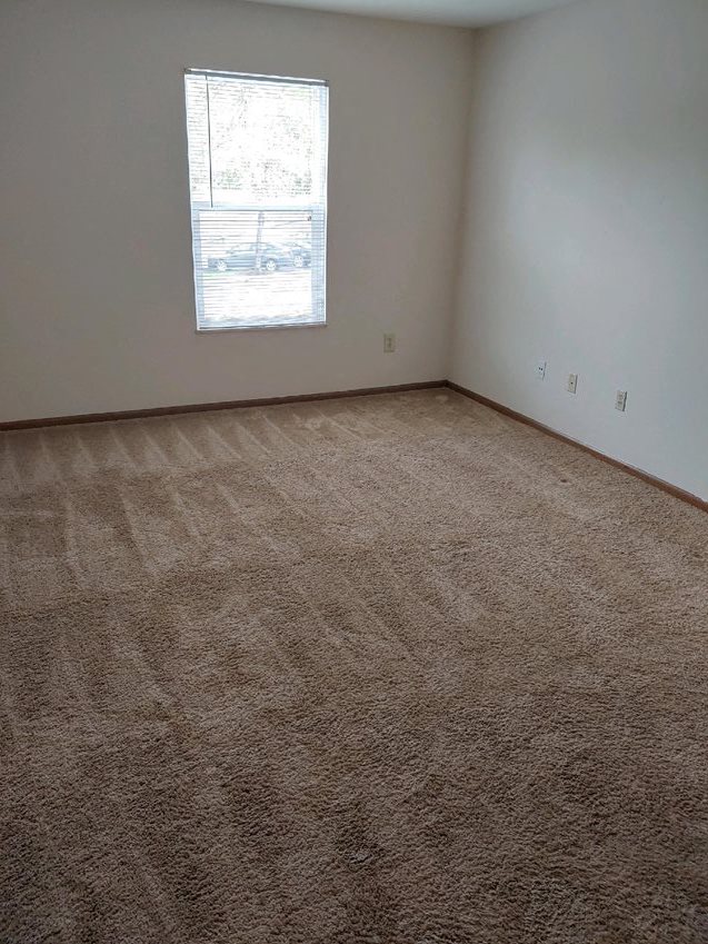 an empty room with carpet and a window