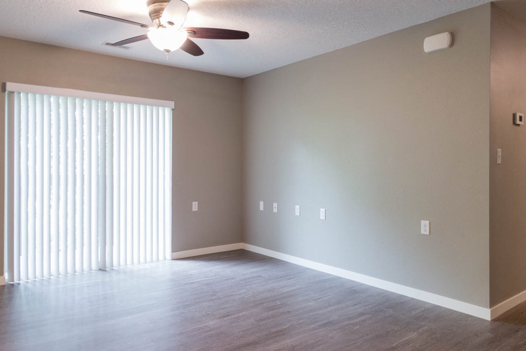 a living room with a ceiling fan and a large window