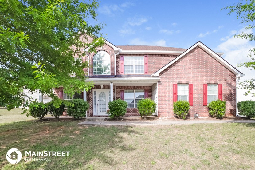 a red brick house with red shutters and a lawn