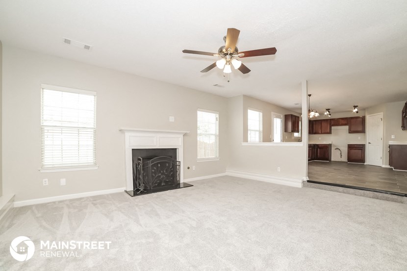a living room with a fireplace and a ceiling fan