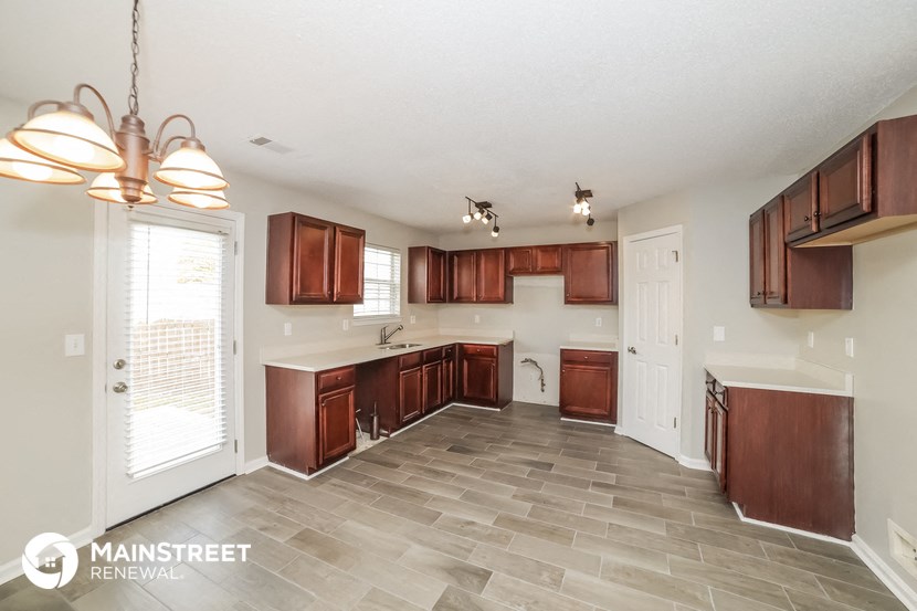 a kitchen with wood cabinets and tile flooring and a door to the living room