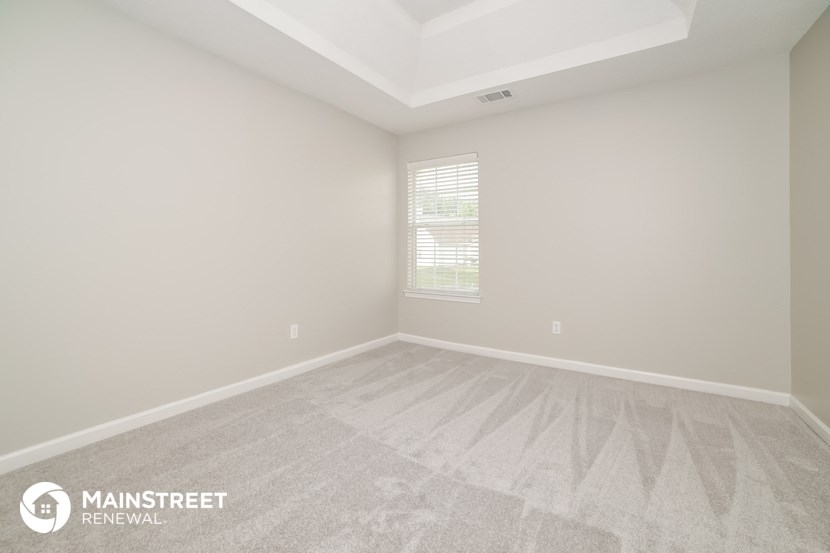 the upstairs bedroom with white carpet and white walls and window