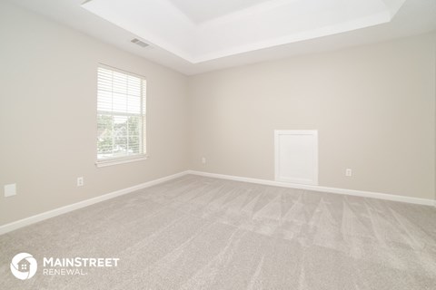 the upstairs living room of a new home with carpet and a window