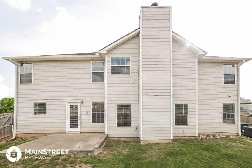 the outside of a white house with a ramp and grass