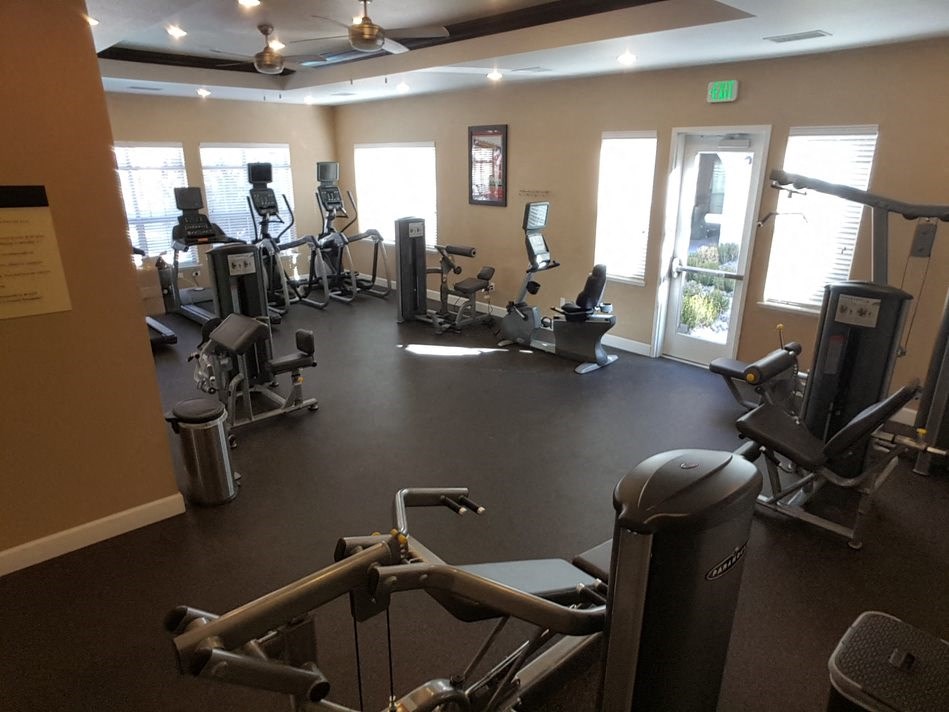 a gym with cardio equipment and windows in a building