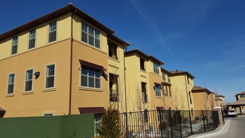 a row of yellow houses with a fence and a blue sky