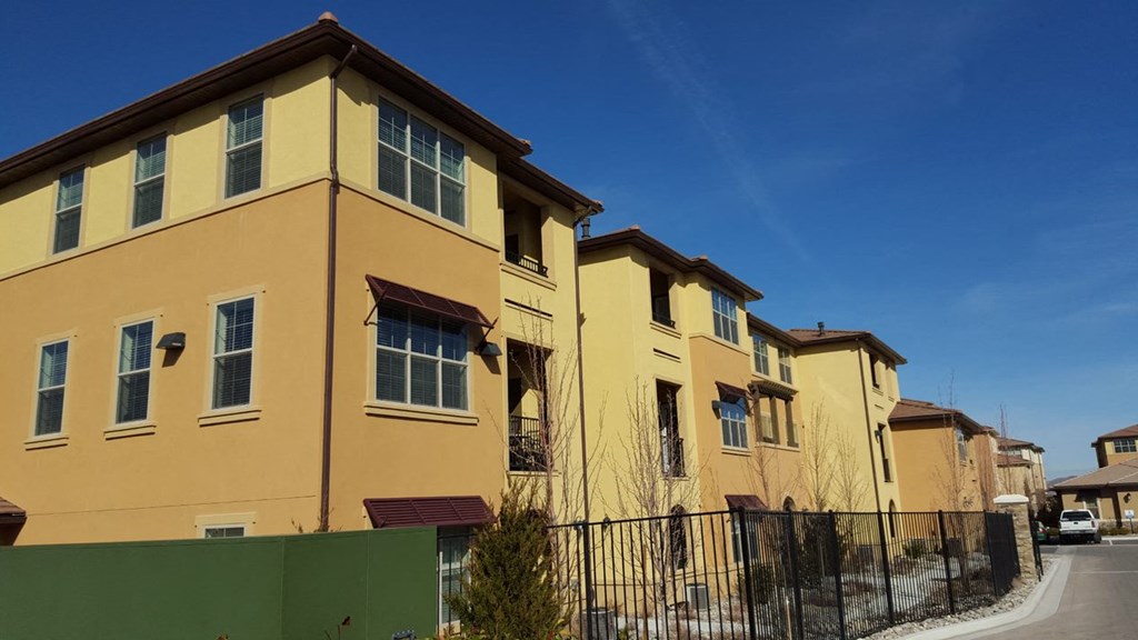 a row of yellow houses with a fence and a blue sky