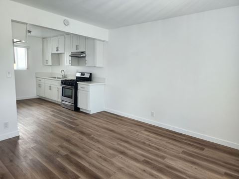 an empty kitchen with white walls and wooden floors