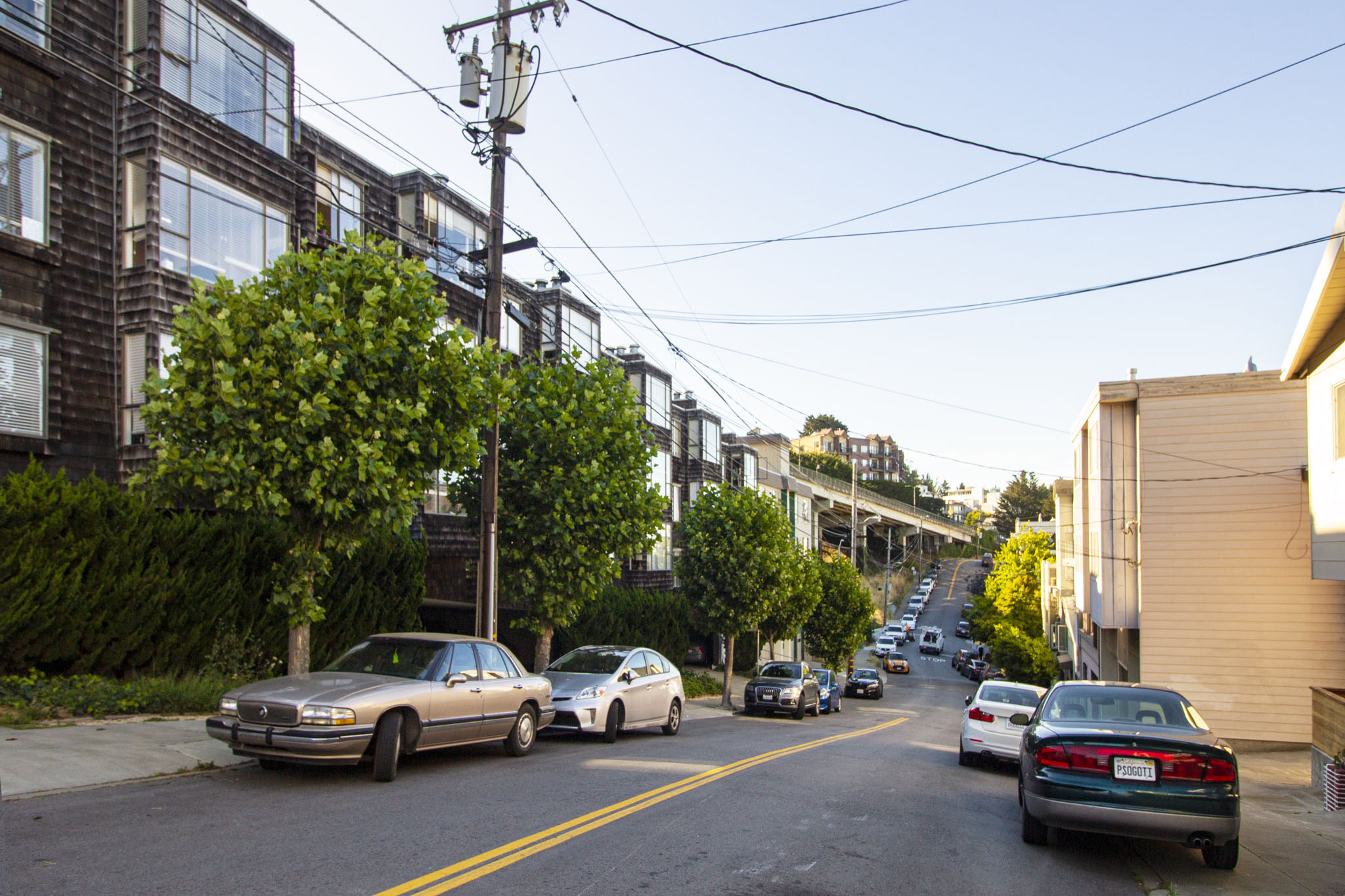 Cars are parked on a street with buildings on the side.