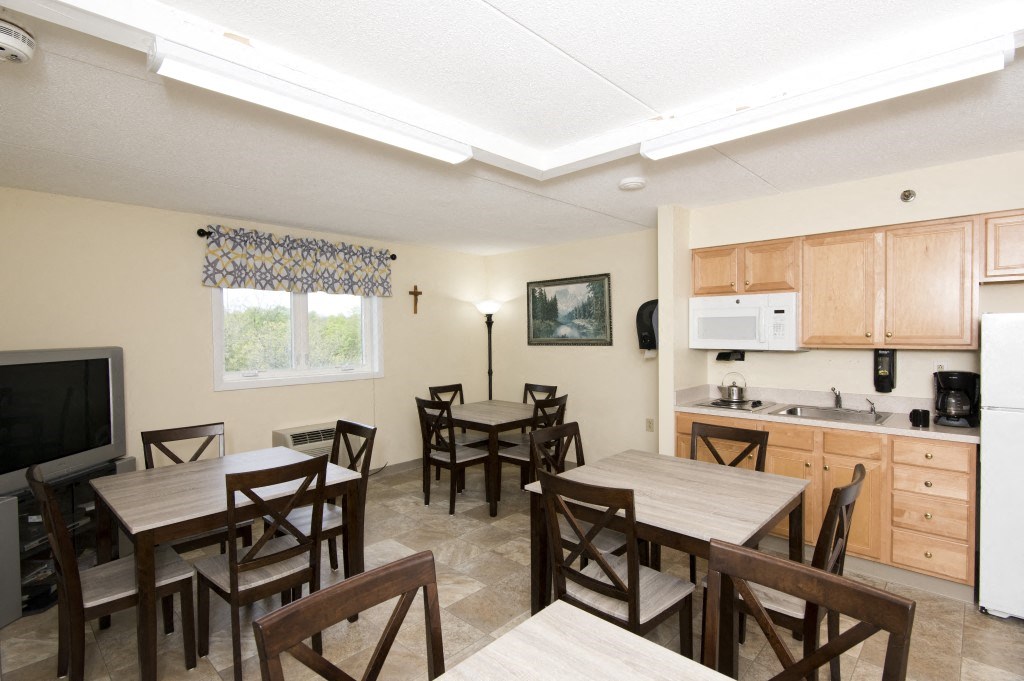 a dining room and kitchen with a table and chairs and a television