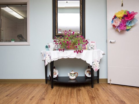 a table with a vase and flowers on it next to a mirror
