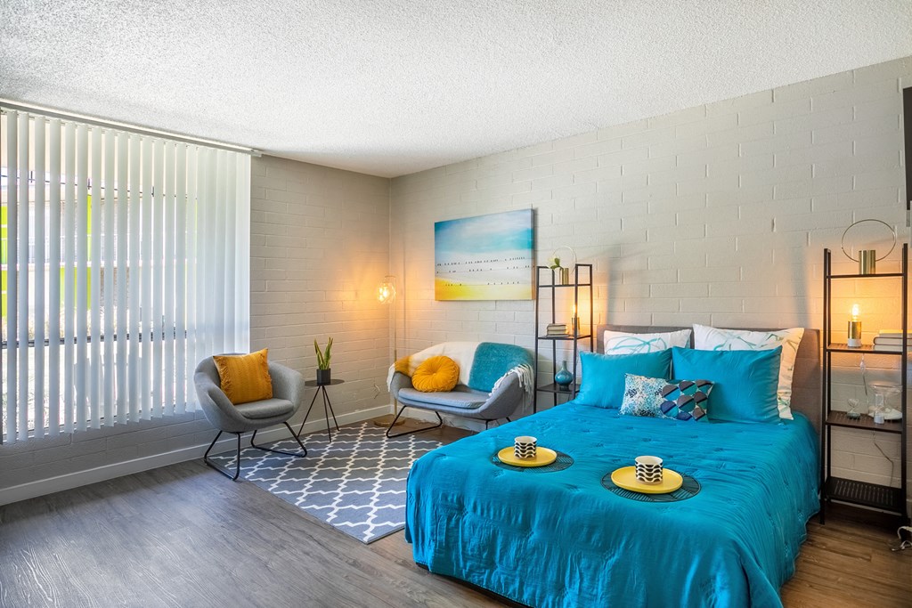 a bedroom with a blue bed and a large window