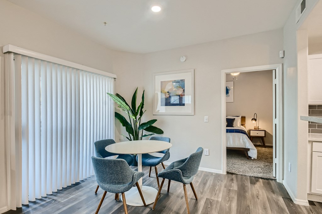 a dining area with a table and chairs and a sliding glass door to a bedroom