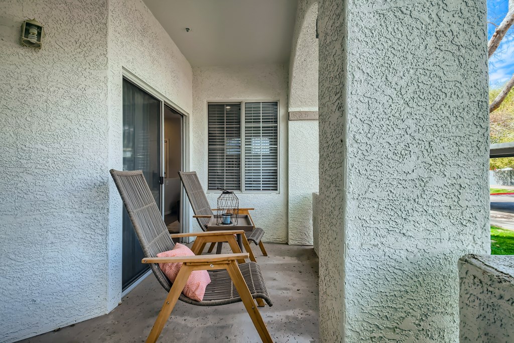 a balcony with two chairs and a table and a window
