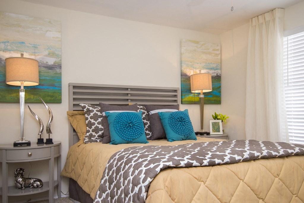 a bedroom with a bed and pillows and paintings on the wall