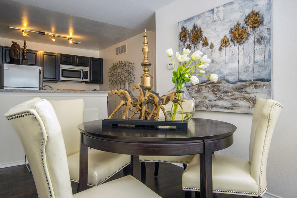 a dining room with white chairs and a table with flowers