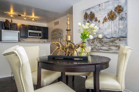 a dining room with white chairs and a table with flowers