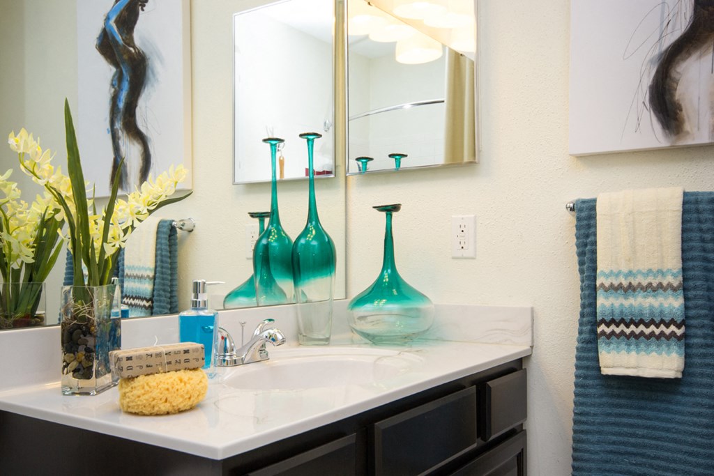a bathroom sink with blue vases and a mirror