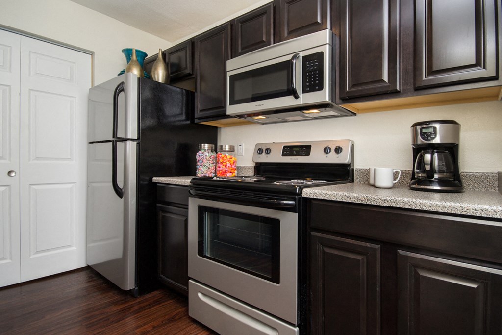 a kitchen with black cabinets and stainless steel appliances and a refrigerator