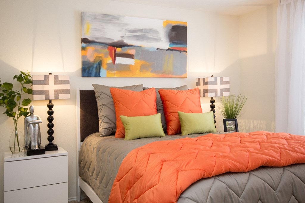 a bedroom with an orange comforter and orange pillows
