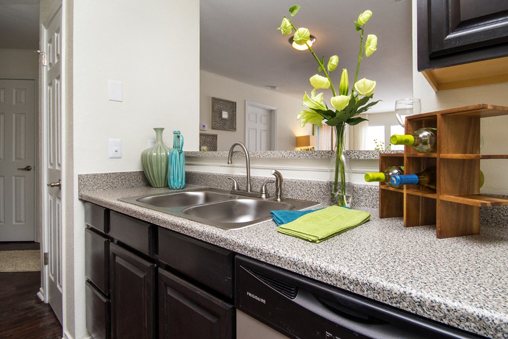 a kitchen with a sink and a counter with a vase of flowers