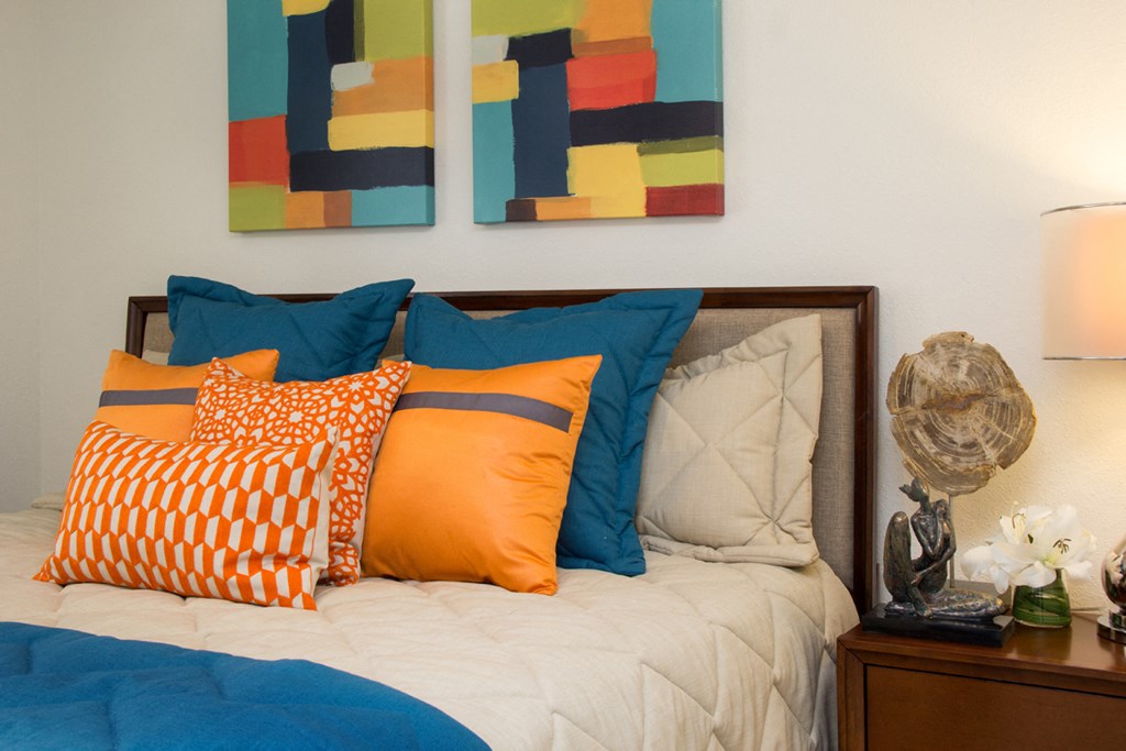 a bed with colorful pillows and paintings on the wall