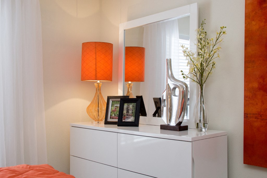 a white dresser with a mirror and lamps on top of it