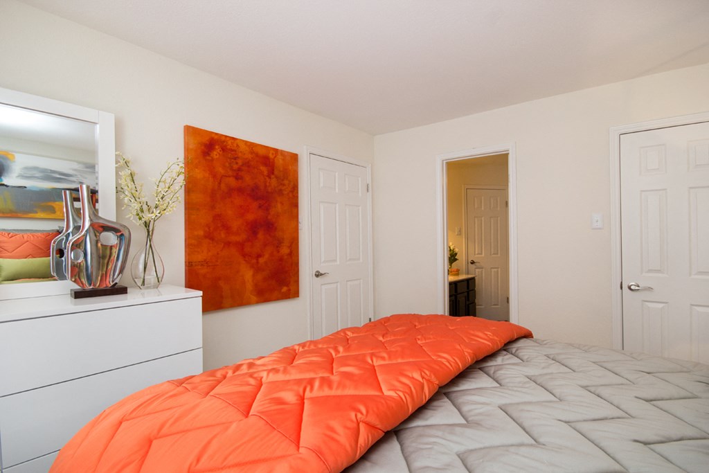 a bedroom with an orange comforter on a bed