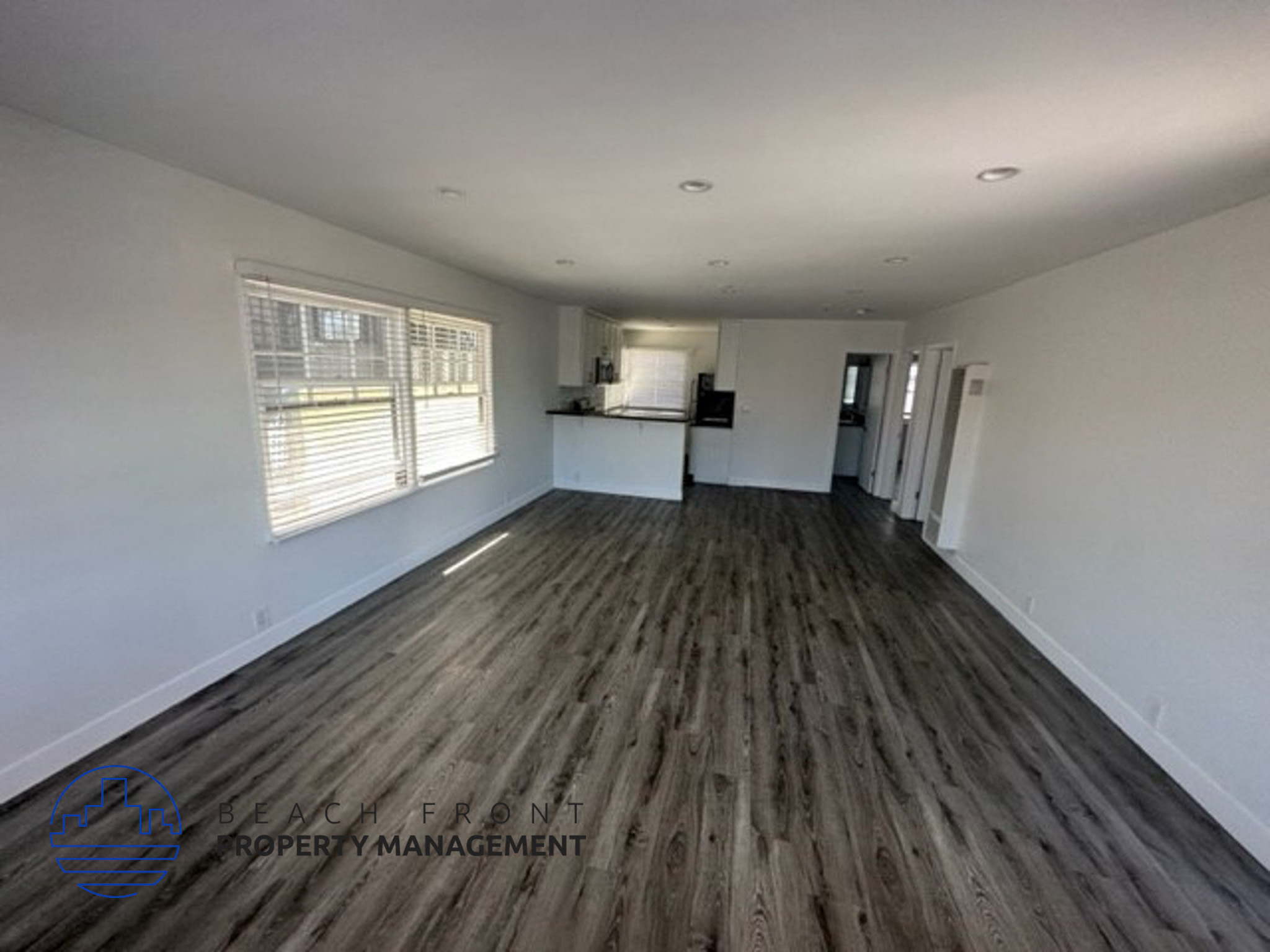 an empty living room with wooden floors and white walls