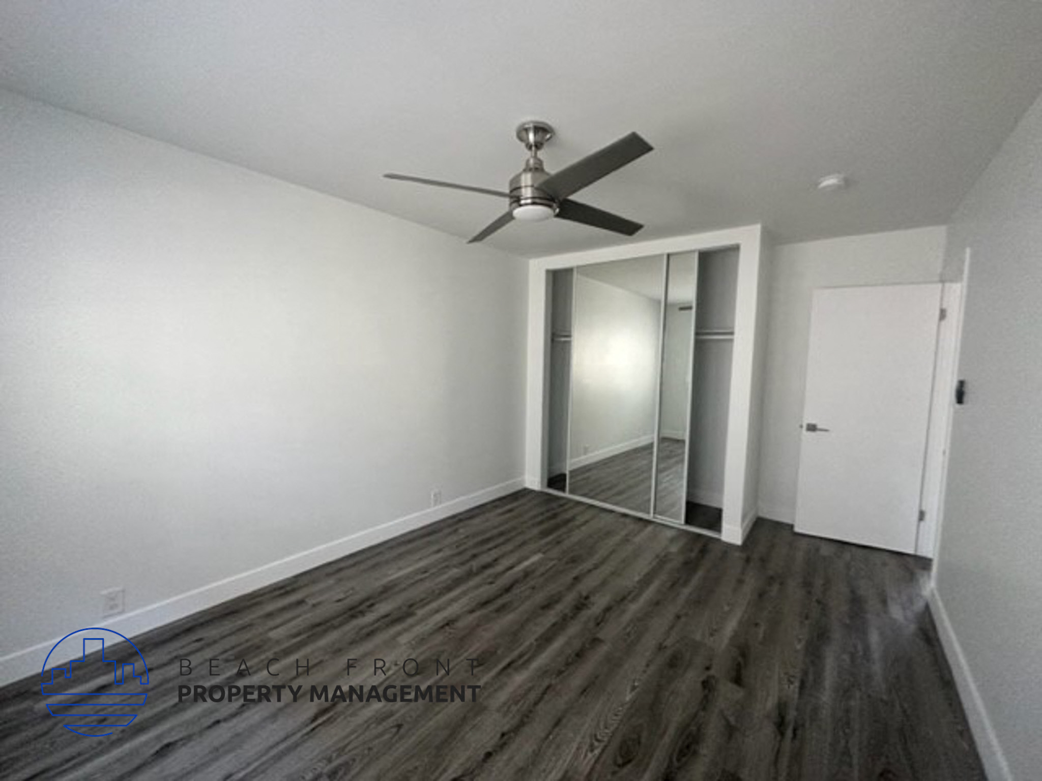 an empty room with a ceiling fan and a mirrored closet