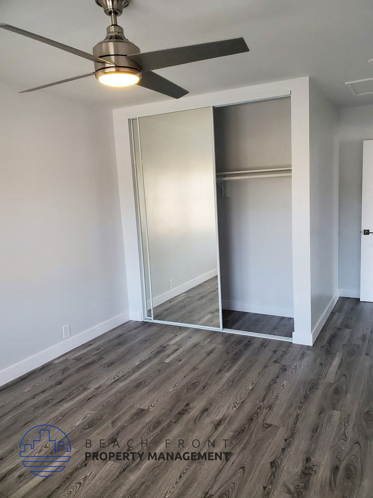 an empty living room with white walls and a ceiling fan