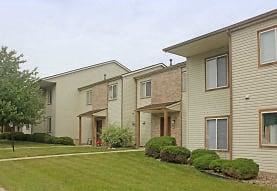 a row of apartment buildings with a green lawn