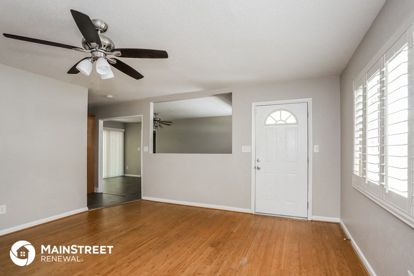 an empty living room with a ceiling fan and a white door