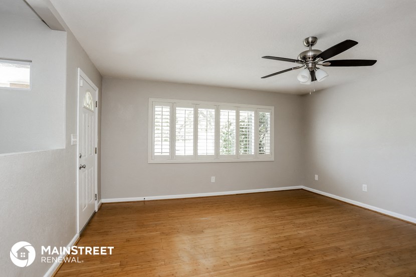 an empty living room with wood floors and a ceiling fan