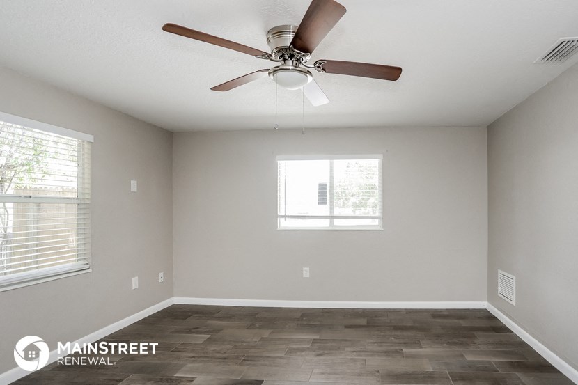 the spacious living room with ceiling fan and window