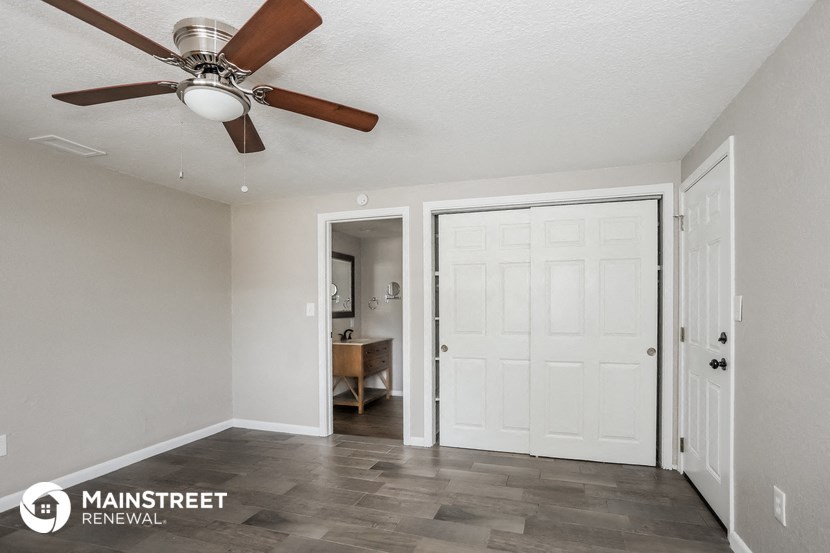 the master bedroom has a ceiling fan and a door to the bathroom
