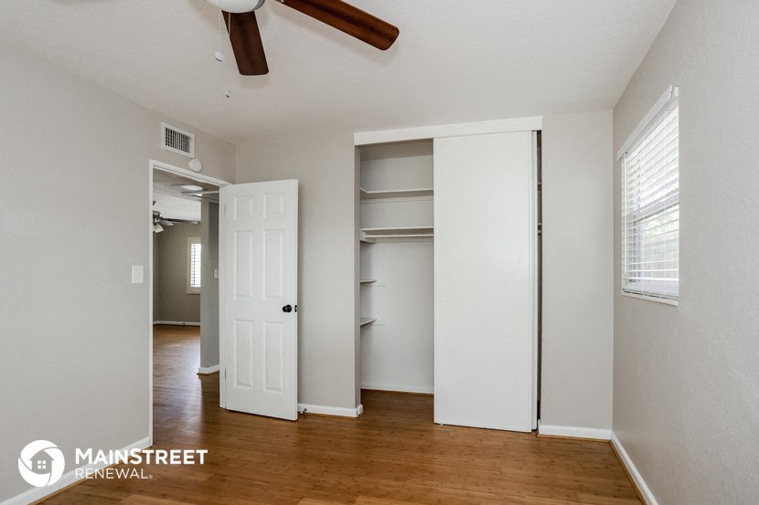 the master bedroom has a large closet with shelves and a ceiling fan