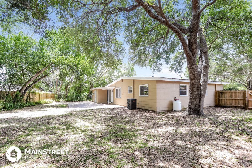 a small tan house with a tree and a driveway