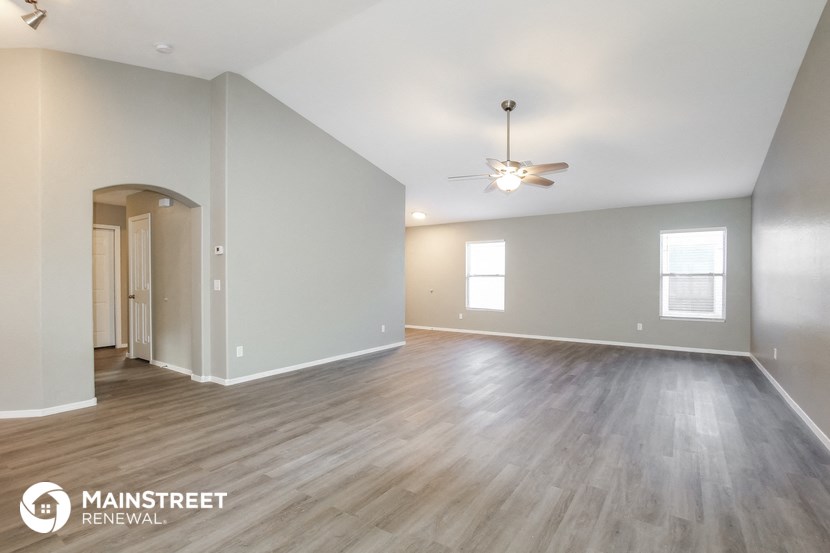 the living room and dining room with wood flooring and a ceiling fan