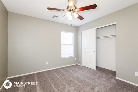 the spacious living room with carpet and a ceiling fan
