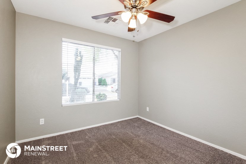 the spacious living room has a ceiling fan and a large window