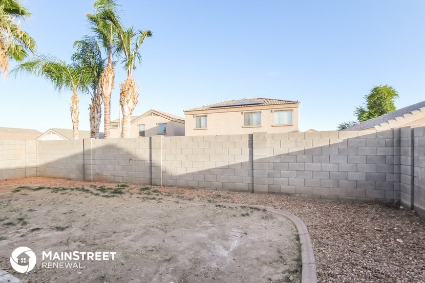 a retaining wall in front of a house with palm trees
