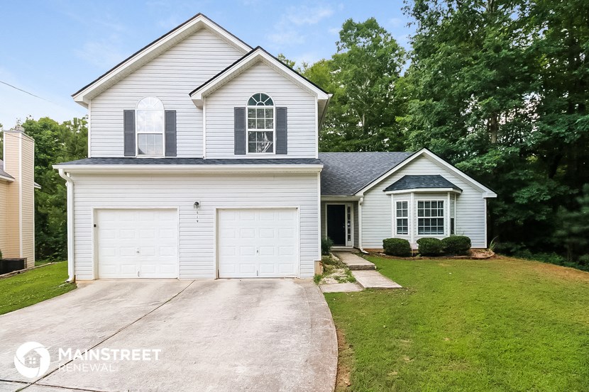 a white house with a white garage door and a lawn